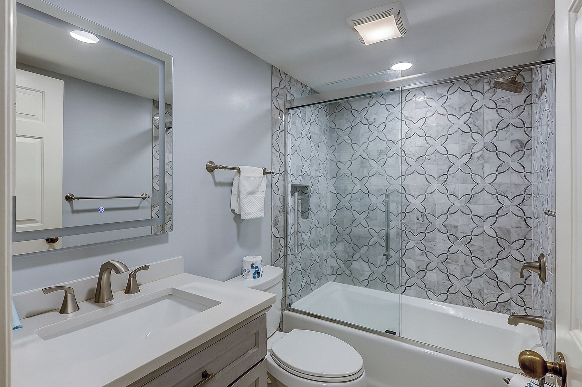 Een moderne badkamer met een douchecabine van glas, een witte wastafel en een toilet.