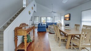 A spacious living room with a staircase, a dining area, and a fireplace. - 4 Beachside Home - Pet Friendly - Coastal Comfort Meets Stylish Island Living (Hilton Head Island)