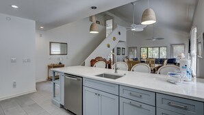 A modern kitchen with a central island, built-in appliances, and a dining area with wicker chairs. - 4 Beachside Home - Pet Friendly - Coastal Comfort Meets Stylish Island Living (Hilton Head Island)