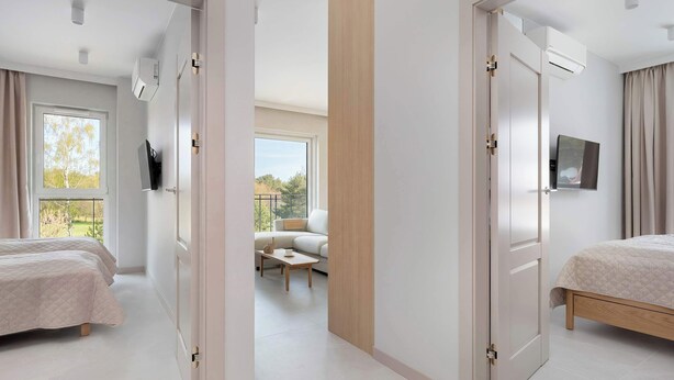 Et moderne hotelværelse med en stor seng, et fjernsyn og en balkon med udsigt over landskabet.