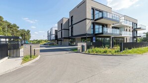 En moderne bygning med flere etager, fladt tag, store vinduer og en låst indgang.