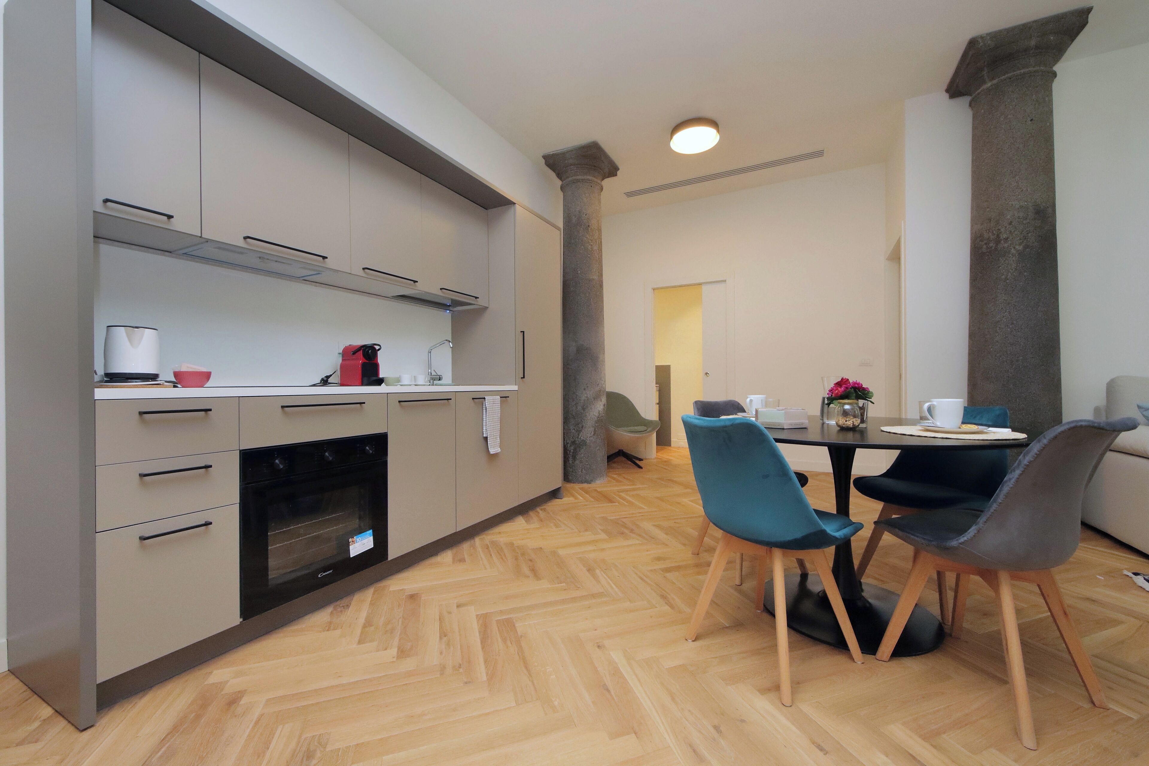 Una cocina moderna con electrodomésticos integrados, un comedor con sillas y un pilar grande.