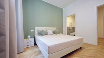 Ein Schlafzimmer mit Bett, Nachttisch, Lampe und Spiegel.