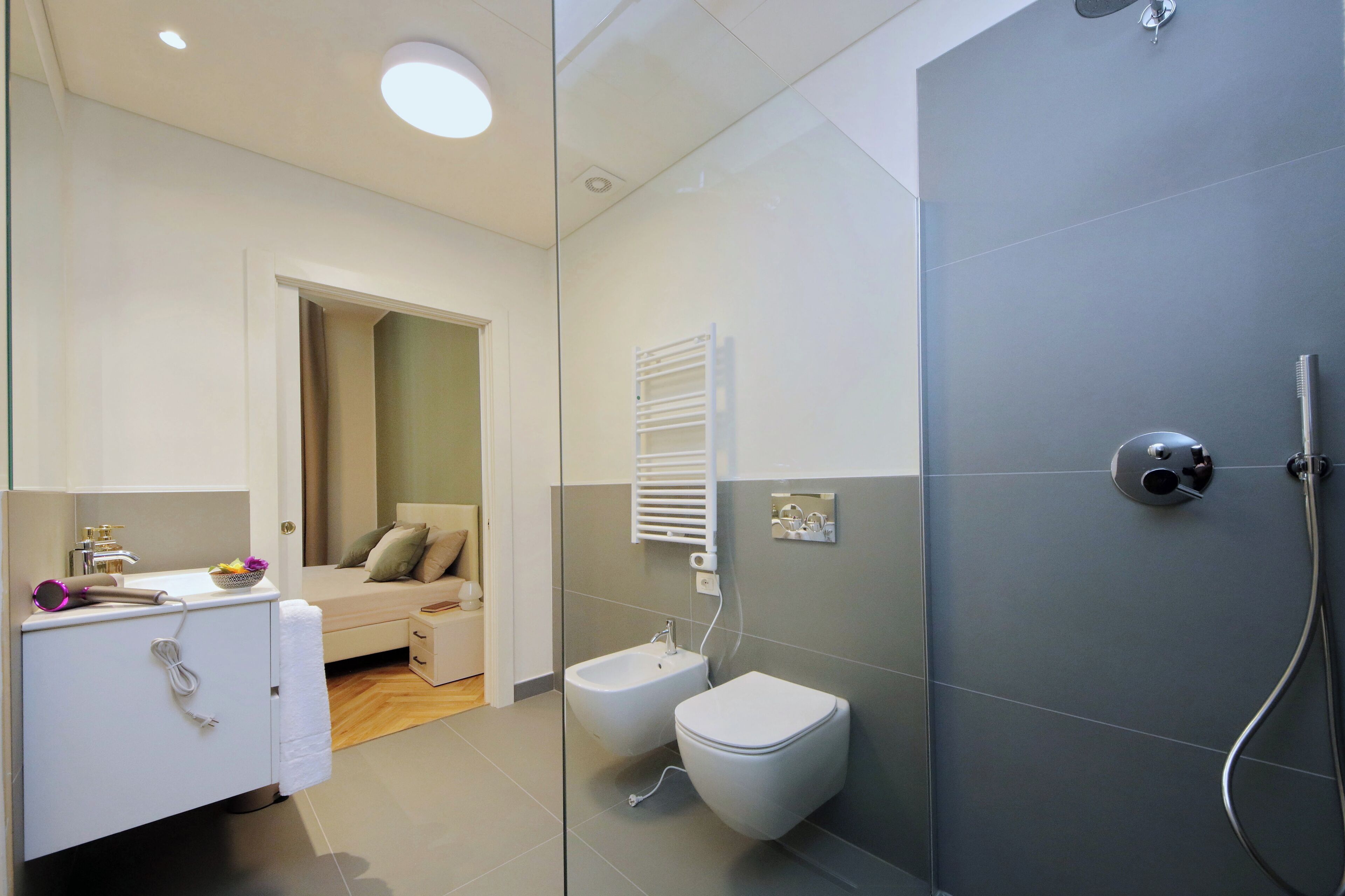 A modern bathroom with a shower, toilet, bidet, and a vanity with a mirror.