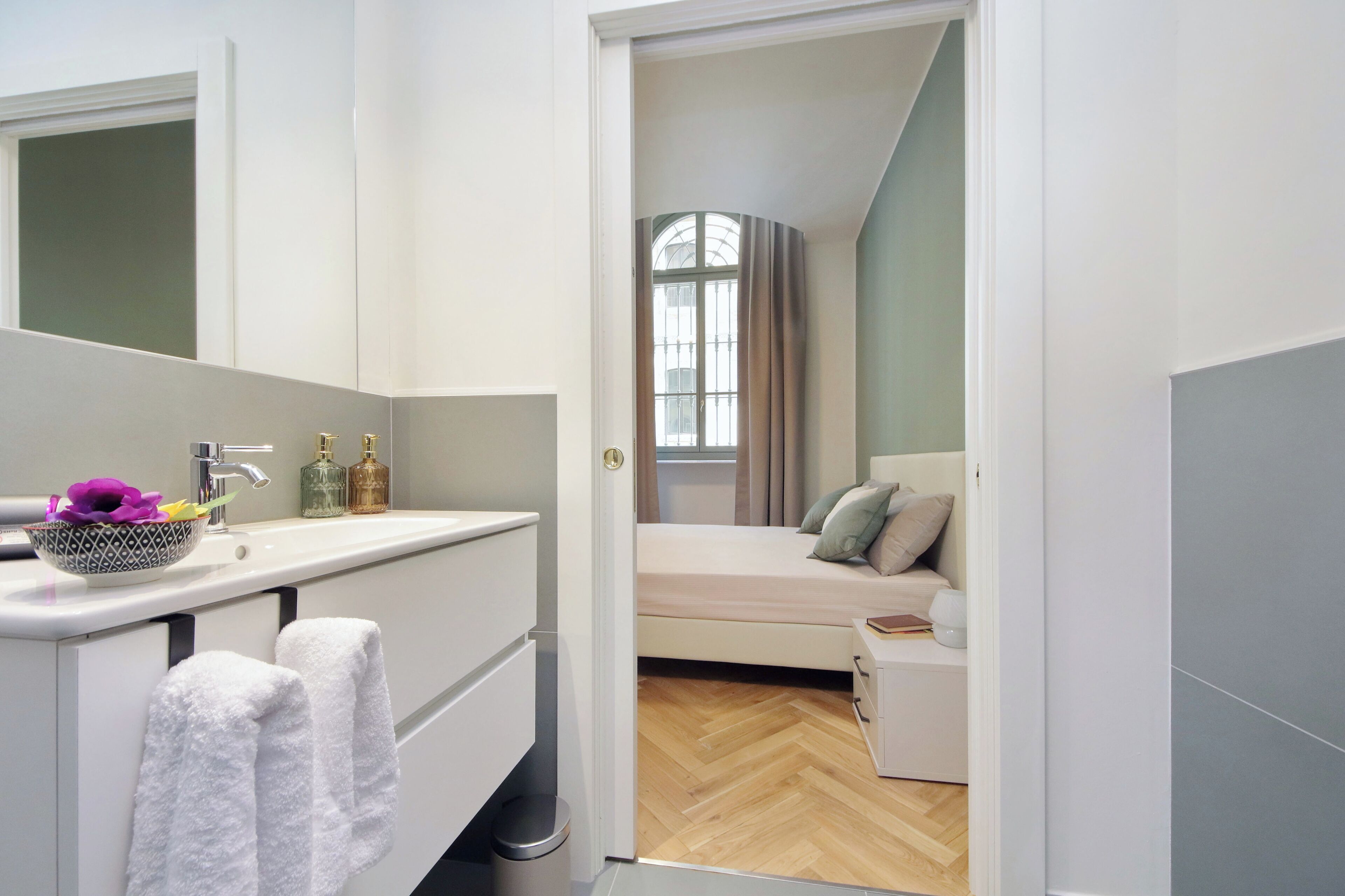 Un baño moderno con lavamanos, espejo y perchero.