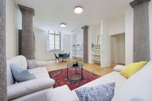 Una sala moderna con un sofá blanco, un tapete rojo estampado y un comedor con mesa y sillas.