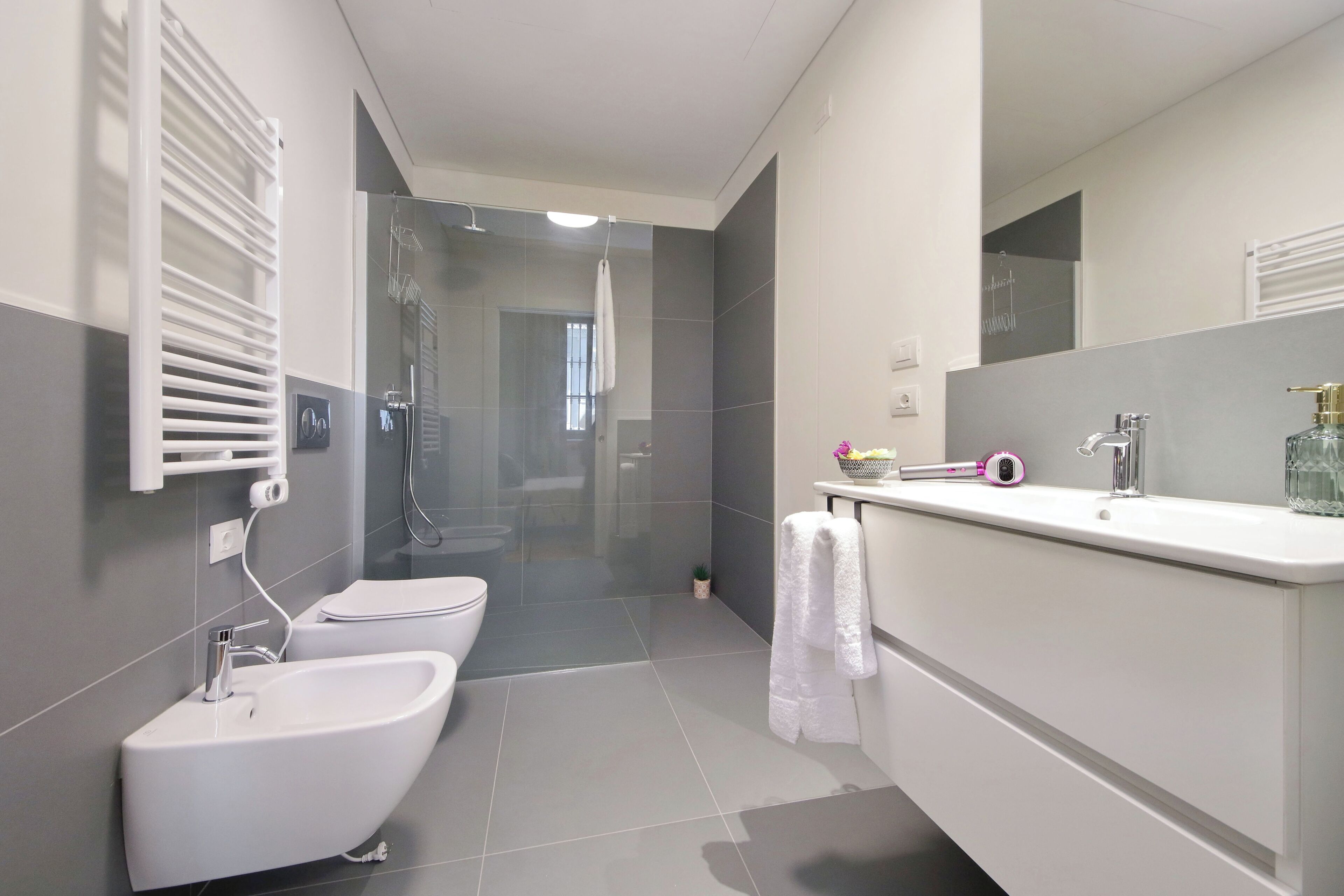 Une salle de bain moderne équipée d’un bidet, de toilettes, d’un lavabo et d’un espace douche.