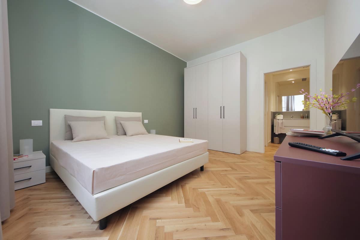 A bedroom with a bed, a desk, and a wardrobe.