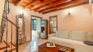 A cozy living room with a wooden ceiling, a white sofa, a wooden coffee table, and a staircase with wrought iron railings. - Country House 'Gran Drago' with Sea View, Wi-Fi and Air Conditioning (Villa de Valverde)