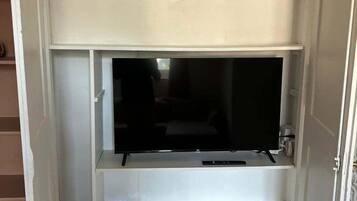 Un meuble de rangement blanc pour appareils multimédias, doté d’un téléviseur à écran plat, d’étagères intégrées et d’une petite table.
