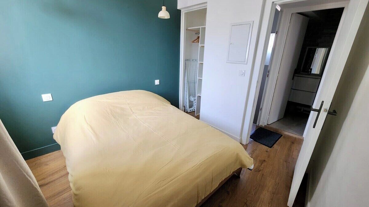 A bedroom with a bed, a wardrobe, and a door leading to a bathroom.