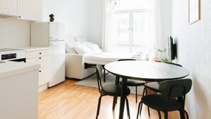 Cozinha compacta e moderna, com armários brancos e um espaço de refeições com mesa redonda e quatro cadeiras.