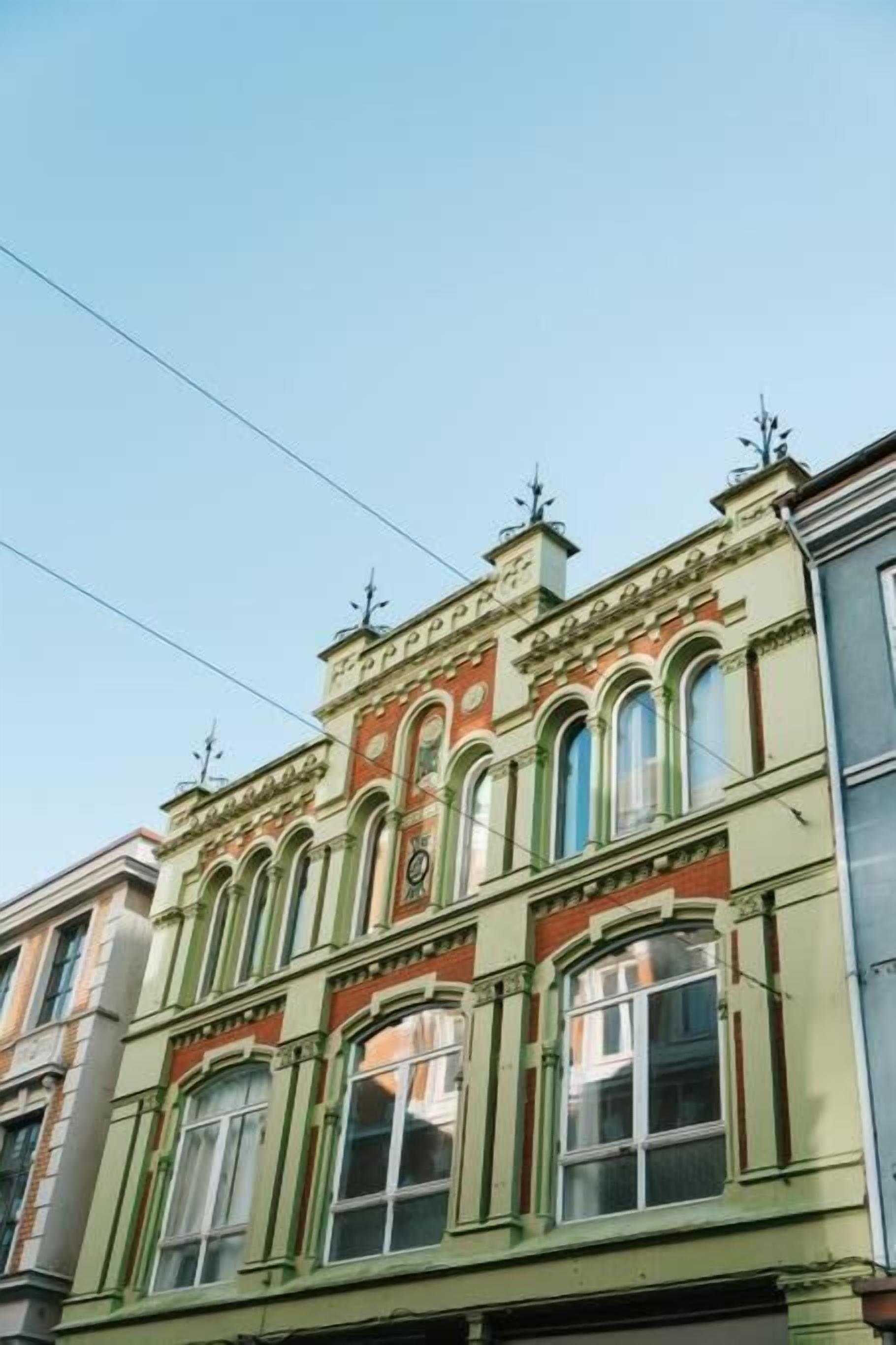 Un edificio con detalles arquitectónicos ornamentales, incluyendo ventanas arqueadas y elementos decorativos en la fachada.