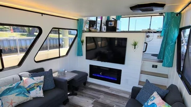 A compact living area with a sofa set, a flat-screen TV, and a small kitchen area. - 🛥Stay Where The Water Meets Relaxation! (Panama City)