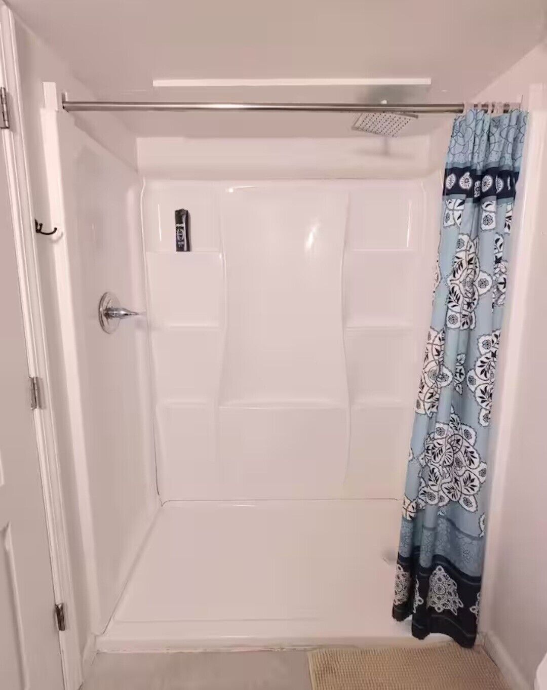 Une douche à l’italienne avec une porte en verre, un panneau de commande et un rideau de douche à motifs.