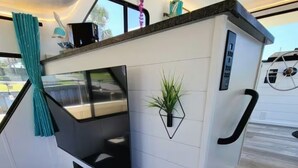 A compact, modern interior with a built-in TV, a small plant, and a bench. - 🛥Stay Where The Water Meets Relaxation! (Panama City)