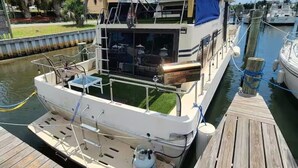 A boat docked at a marina with a covered deck area, a small cabin, and a water filtration system. - 🛥Stay Where The Water Meets Relaxation! (Panama City)