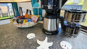 A kitchen counter with a coffee maker, a tray of snacks, and a salt and pepper shaker set. - 🛥Stay Where The Water Meets Relaxation! (Panama City)