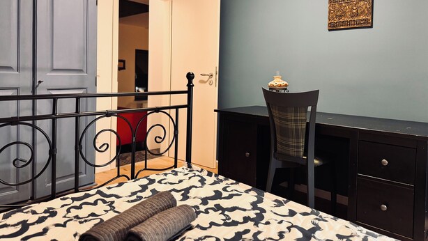 A bedroom with a bed, a desk, and a wardrobe.
