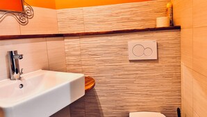 A bathroom with a white sink, a toilet, and a wooden vanity.