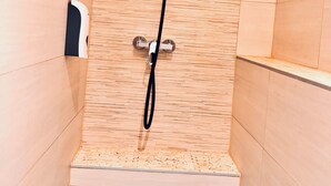 A shower with a handheld showerhead and a fixed wall-mounted showerhead, with a soap dispenser on the wall.