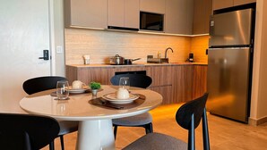 A modern kitchen with a dining table, chairs, a refrigerator, and a microwave.