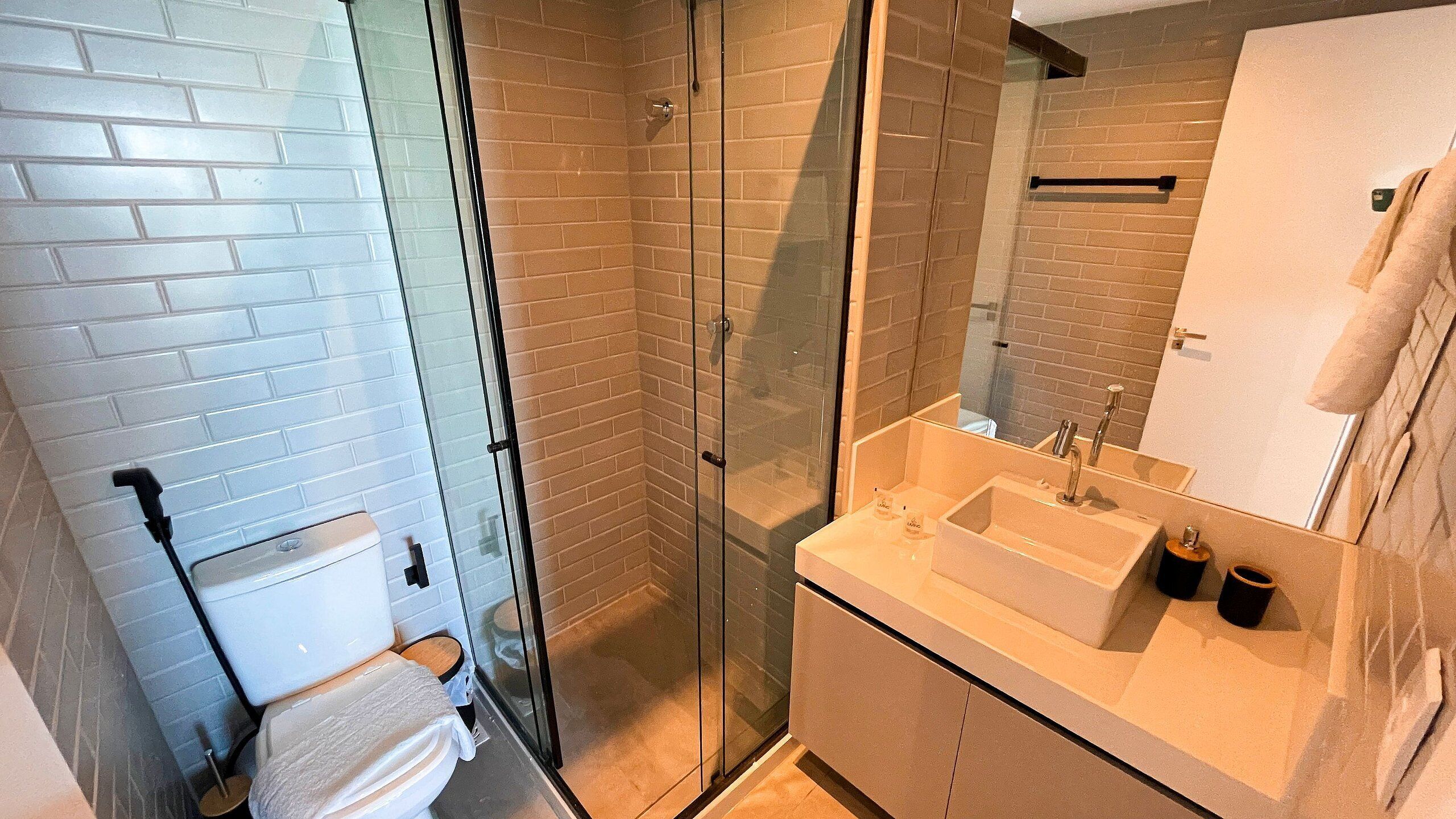 Une salle de bain avec une douche à parois de verre, des toilettes blanches et un lavabo avec un miroir.