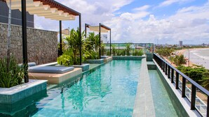 A swimming pool with a stone wall and a view of the beach.