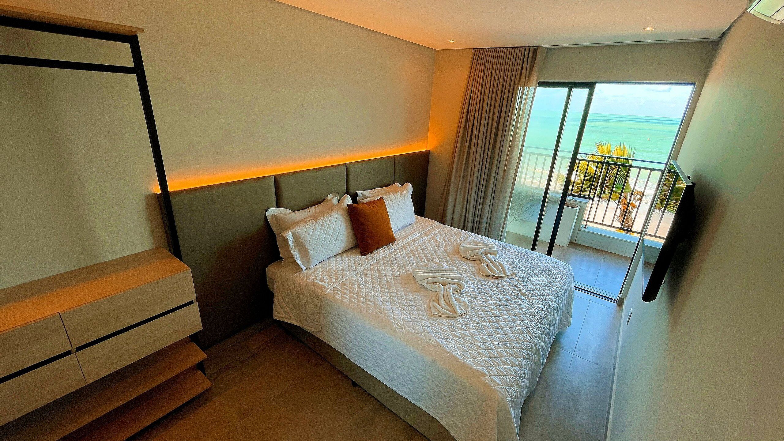 Habitación de hotel con cama, televisión, balcón con vistas y una escalera.