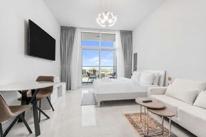 Ein modernes Hotelzimmer mit Bett, Schreibtisch, Sofa und großem Fenster mit Blick auf die Stadt.