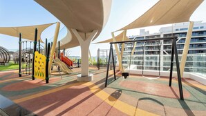 A playground with swings and slides, surrounded by modern architecture. - StayShort - Premium New Arjan Studio - sleeps 3 (Arjan)