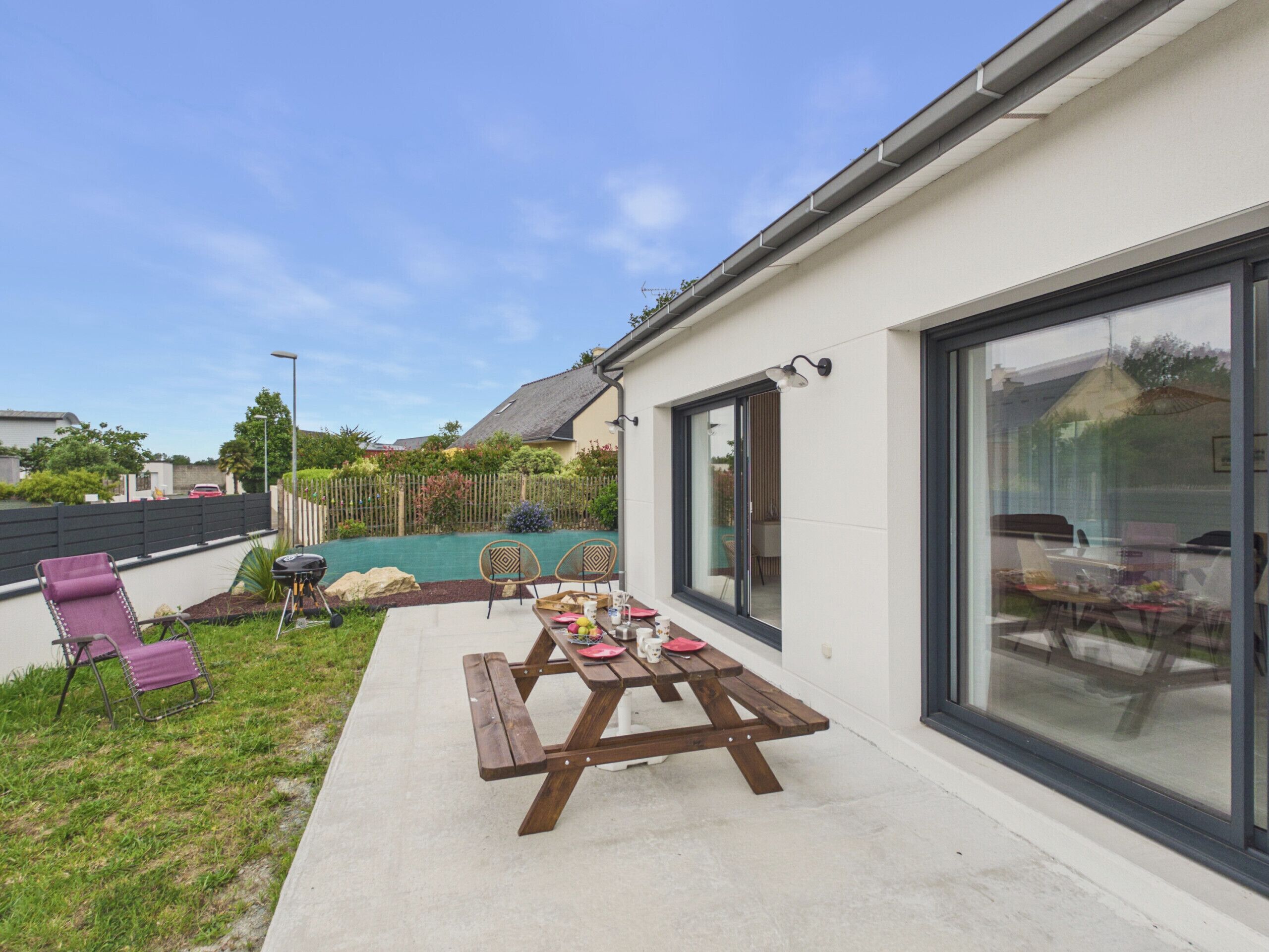 A patio with a picnic table, chairs, and a small garden area.