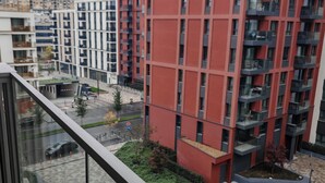 A modern apartment building with balconies, a green lawn, and a patterned pavement. - Belgrade Waterfront Lux 3  (Belgrade)