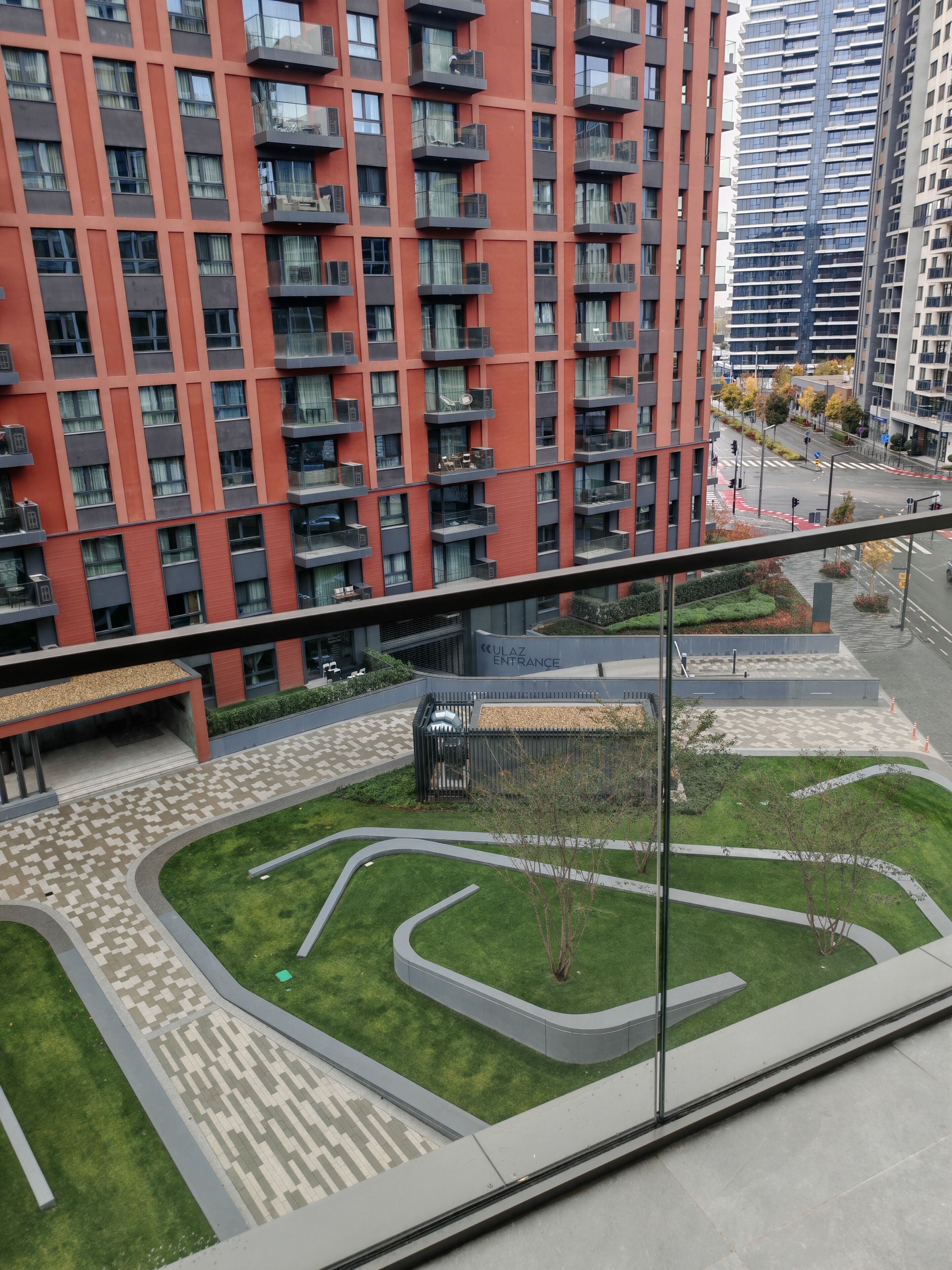 Een hoog appartementencomplex met verschillende balkons, een aangelegde binnentuin en een heldere lucht.