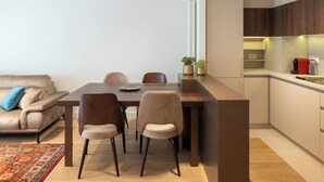 A modern kitchen with a dining area, featuring a wooden table, chairs, and a built-in island with a sink. - Belgrade Waterfront Lux 3  (Belgrade)