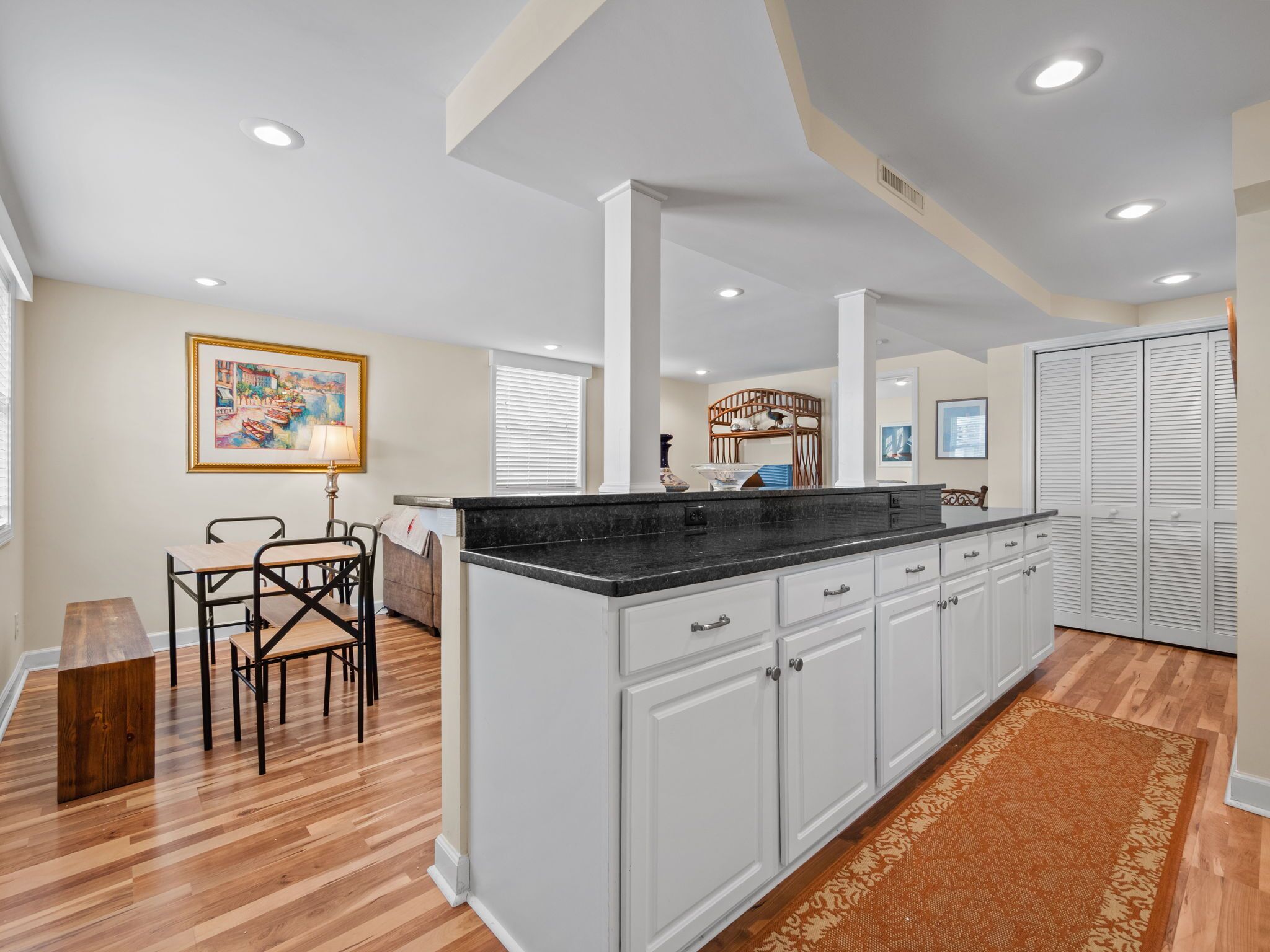 A spacious kitchen with white cabinets, a black countertop, and a wooden dining table.