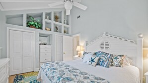 Een slaapkamer met een bed, een witte garderobe, een plafondventilator en inbouwplanken met planten.