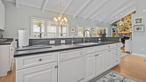 Een moderne keuken met witte kastjes, een granieten aanrechtblad en een inbouw vaatwasser.