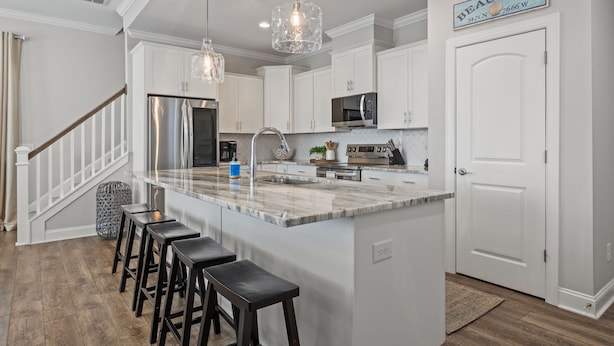 A modern kitchen with white cabinets, a large island with bar stools, stainless steel appliances, and pendant lighting. - Beautime-Pet Friendly Home in Downtown Beaufort, NC (Beaufort)