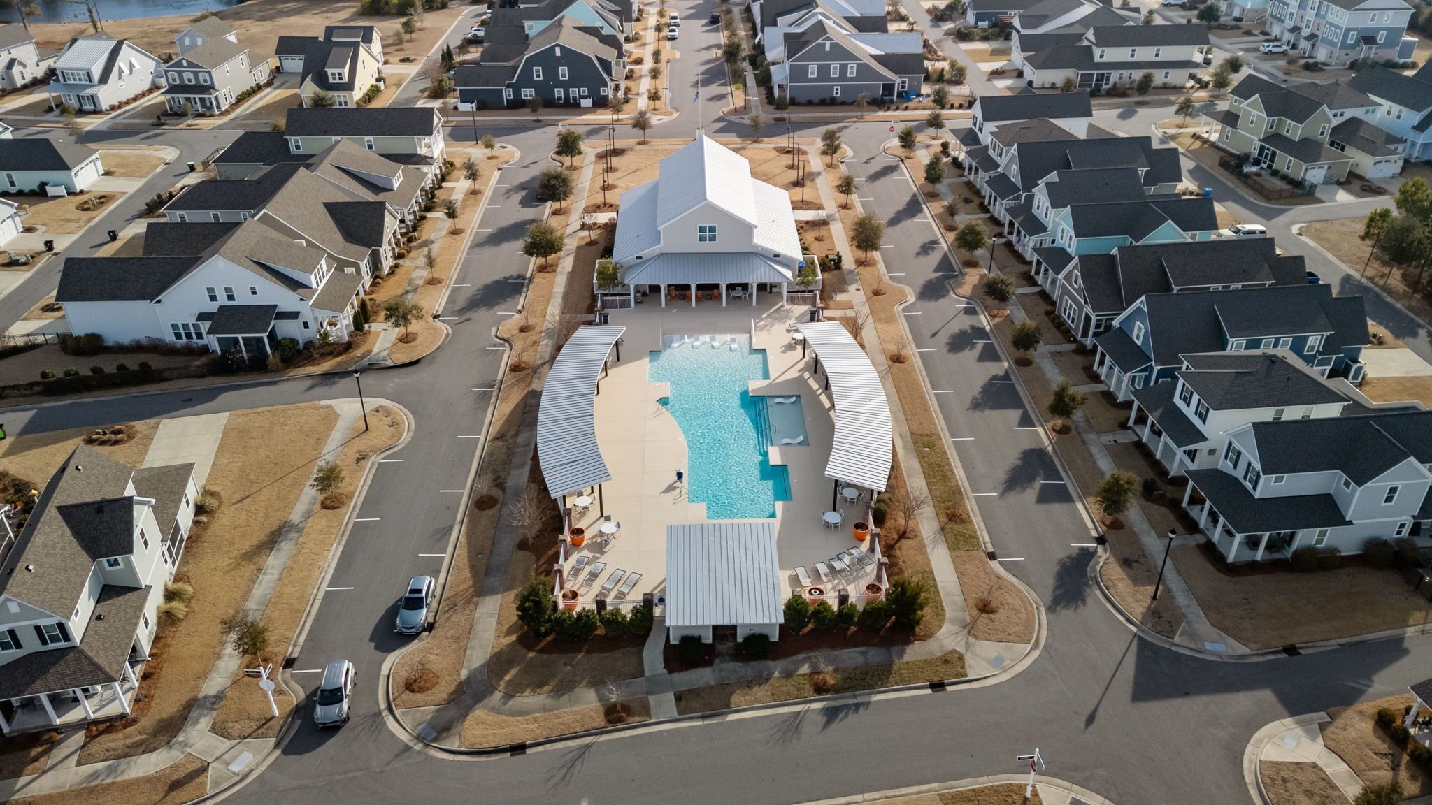 An aerial view of a residential area with a central swimming pool surrounded by houses.