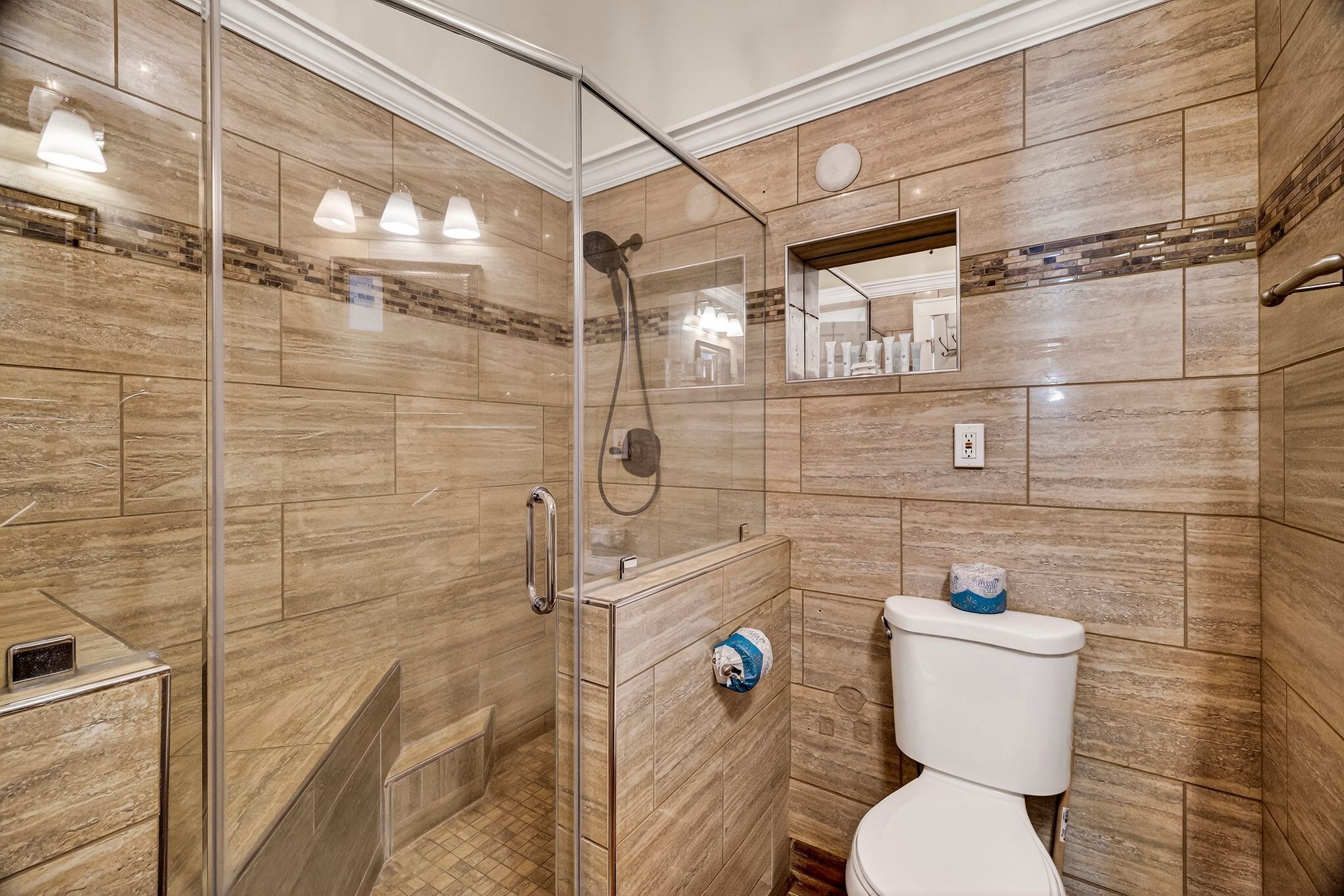 A bathroom with a glass-enclosed shower, a toilet, and a mirror.