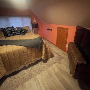 Ein Schlafzimmer mit einem Bett, einem Nachttisch, einer Lampe, einem Fernseher und einer Tür.