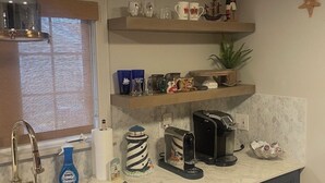 Une cuisine équipée d’un évier, d’une machine à café et d’une étagère décorative où sont exposés divers objets.