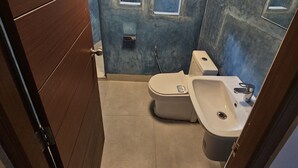 Un baño con inodoro, lavamanos y zona de ducha.