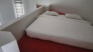 Una habitación con cama, una mesita y una ventana con persianas.