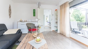 Un saló modern amb un sofà, una taula de centre de fusta, una taula de menjador i una cuina al fons.