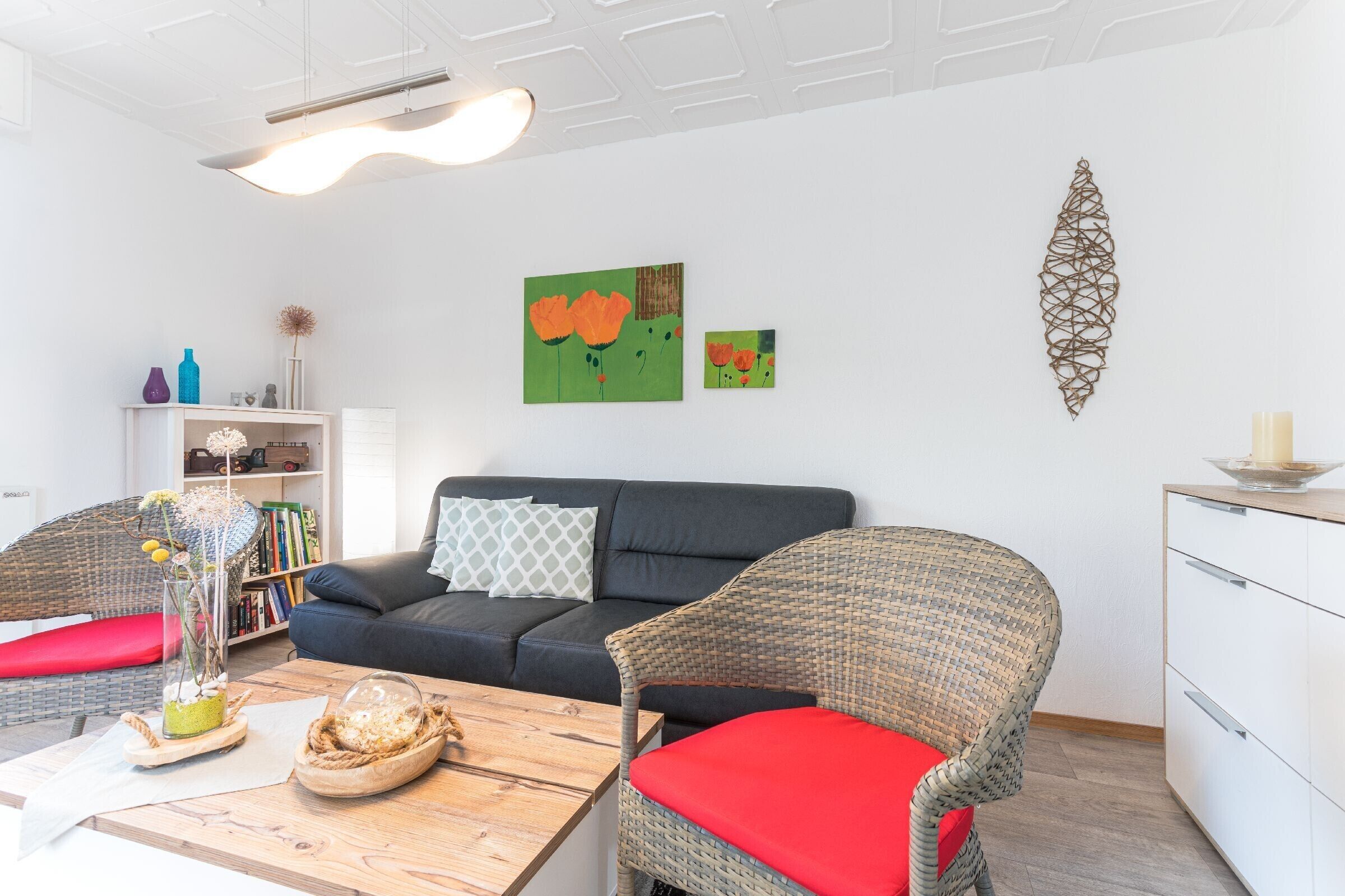 A modern living room with a sofa, wicker chairs, a coffee table, and artwork on the wall.