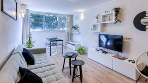 A modern living room with a sofa, a dining table, a TV, and a bookshelf. - Apartment Promenada (Dubrovnik)