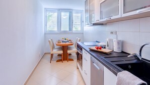 A compact kitchen with a dining table, a built-in oven, and a sink. - Apartment Promenada (Dubrovnik)