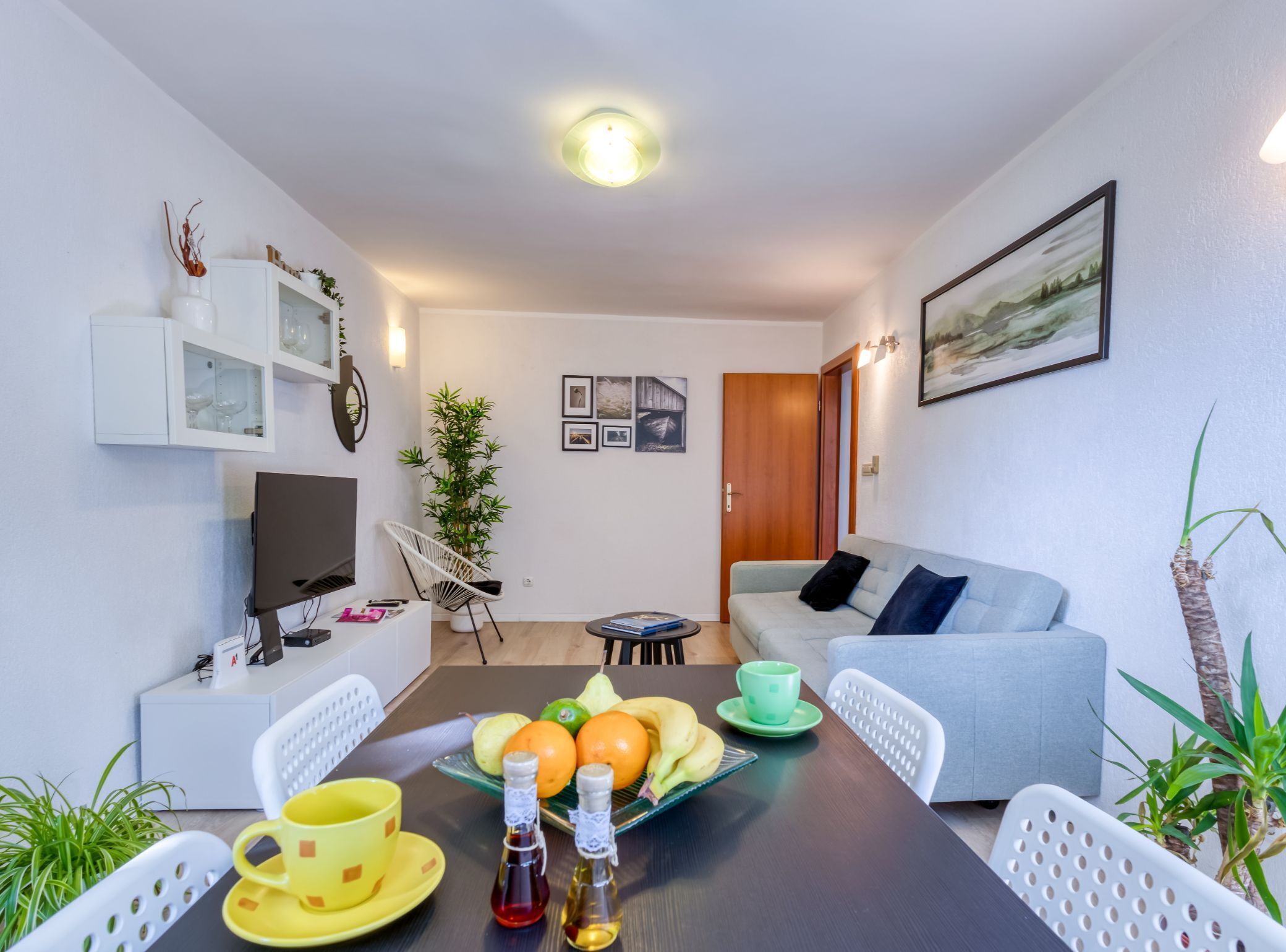A modern living room with a sofa, dining table, and a TV.